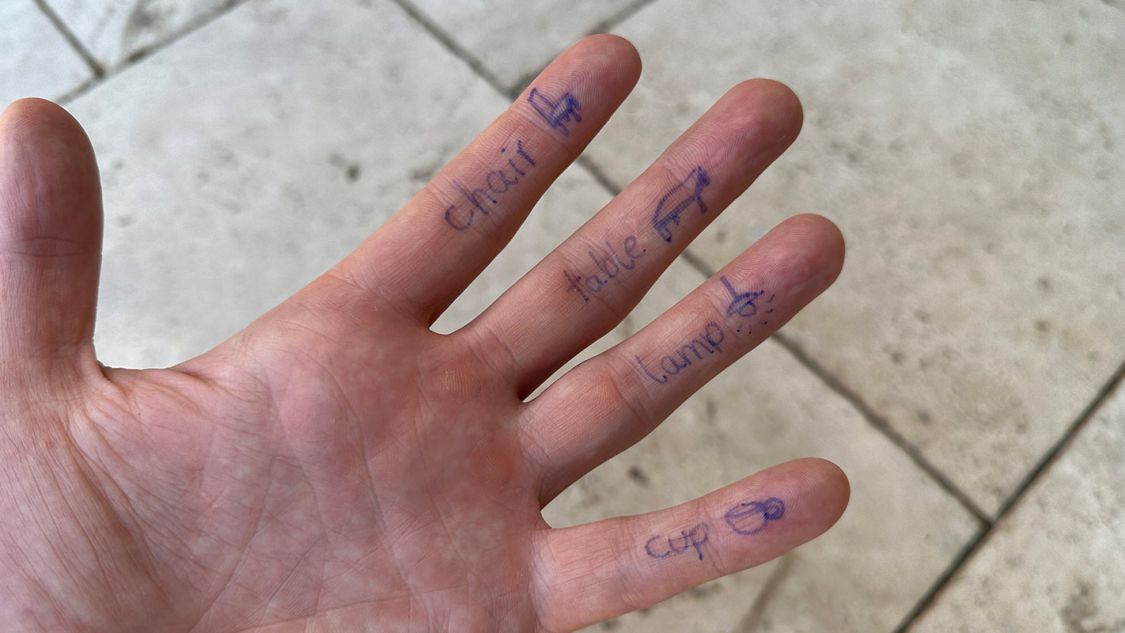Hand mit auf die Finger geschriebene Vokabeln.